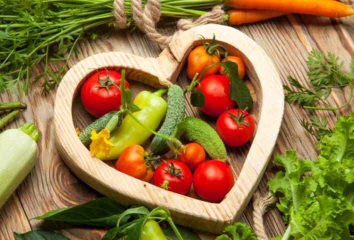 Wooden heart outline with vegetables inside and out.