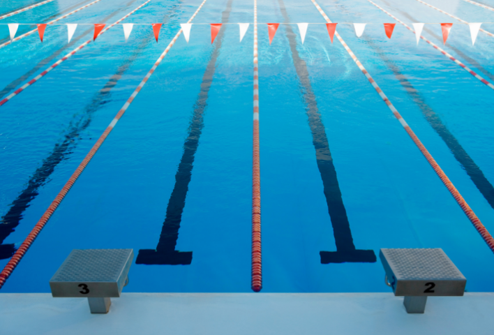 An Olympic size swimming pool with red and white bunting over it.